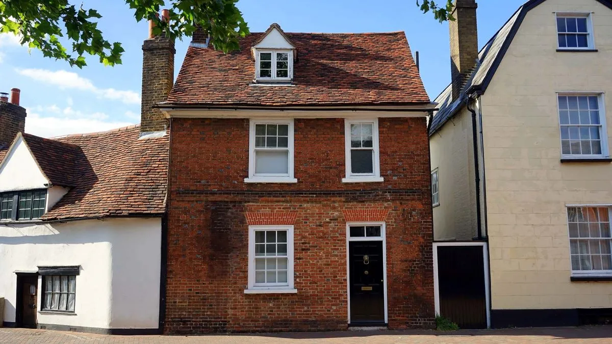 A red-brick terraced house on a sunny UK street
